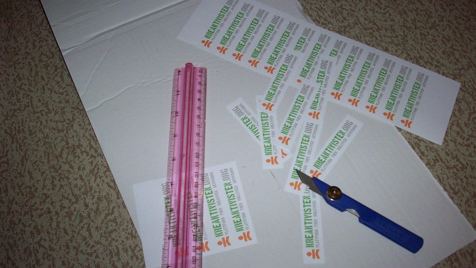 Ausgeschnitte Sticker neben Cuttermesser auf dicker Pappe
